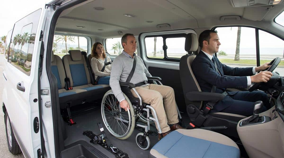 Persona en silla de ruedas viajando anclada con seguridad en el interior de una furgoneta adaptada junto a sus acompañantes.